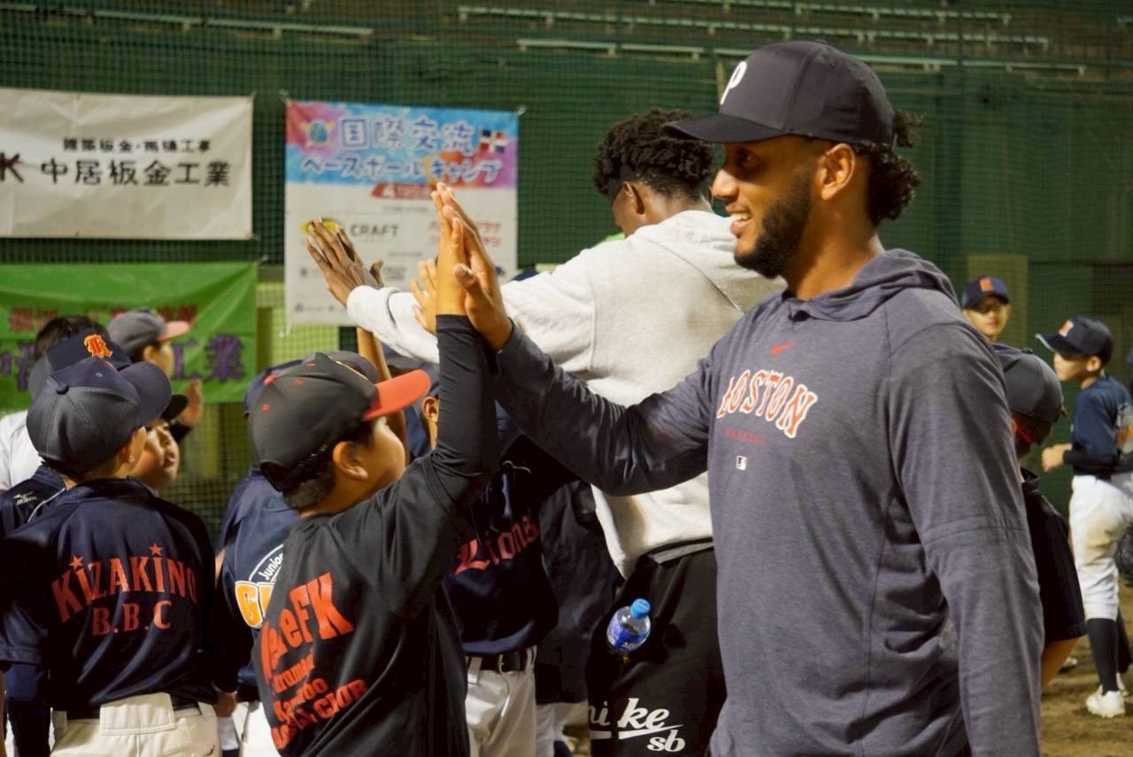 野球場で選手とハイタッチする子どもたち